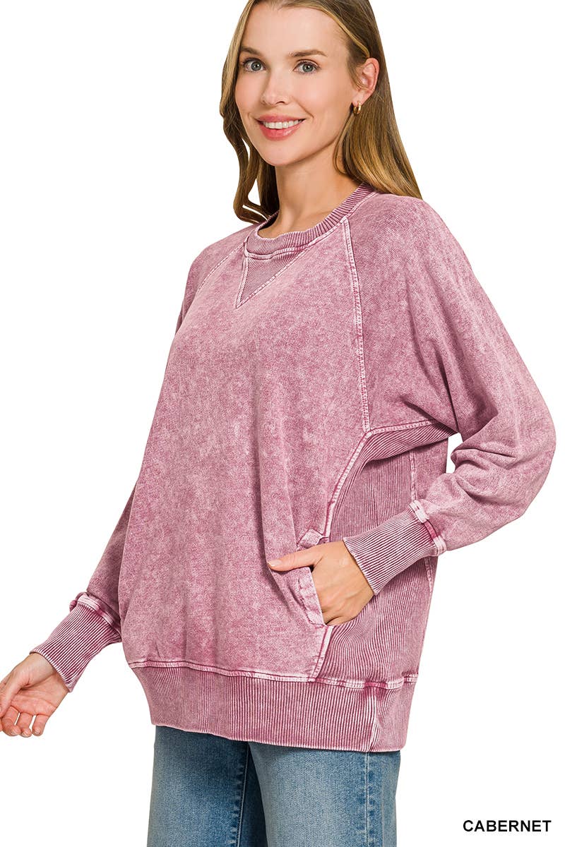 Woman wearing an oversized cabernet washed French terry pullover with raglan sleeves, ribbed cuffs and front pockets, styled with light wash jeans