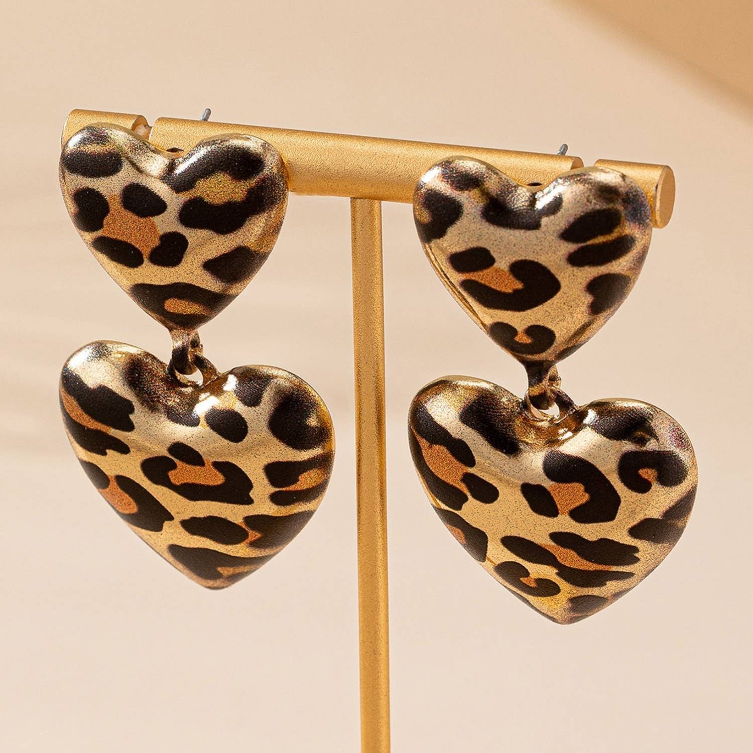 Leopard print heart-shaped earrings on a beige background