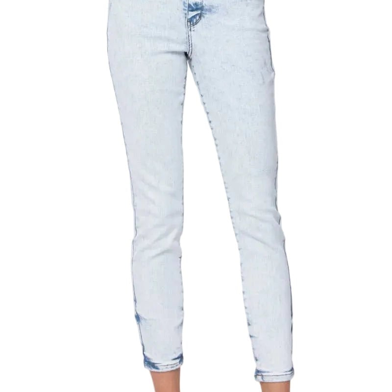 A person wearing light-wash blue skinny jeans with rolled cuffs and brown flat sandals, shown from the waist down against a plain light gray studio background.