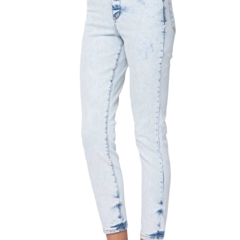 A person wearing light-wash blue acid-wash cropped jeans with brown slide sandals, shown from the waist down against a plain white studio background.