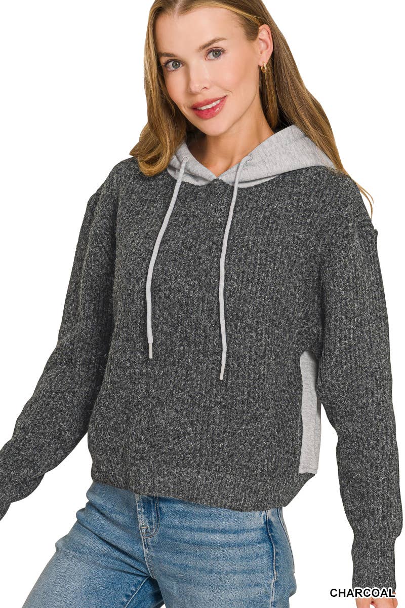 Woman wearing a charcoal textured knit hoodie sweater with a heather gray contrast hood and drawstrings, paired with jeans