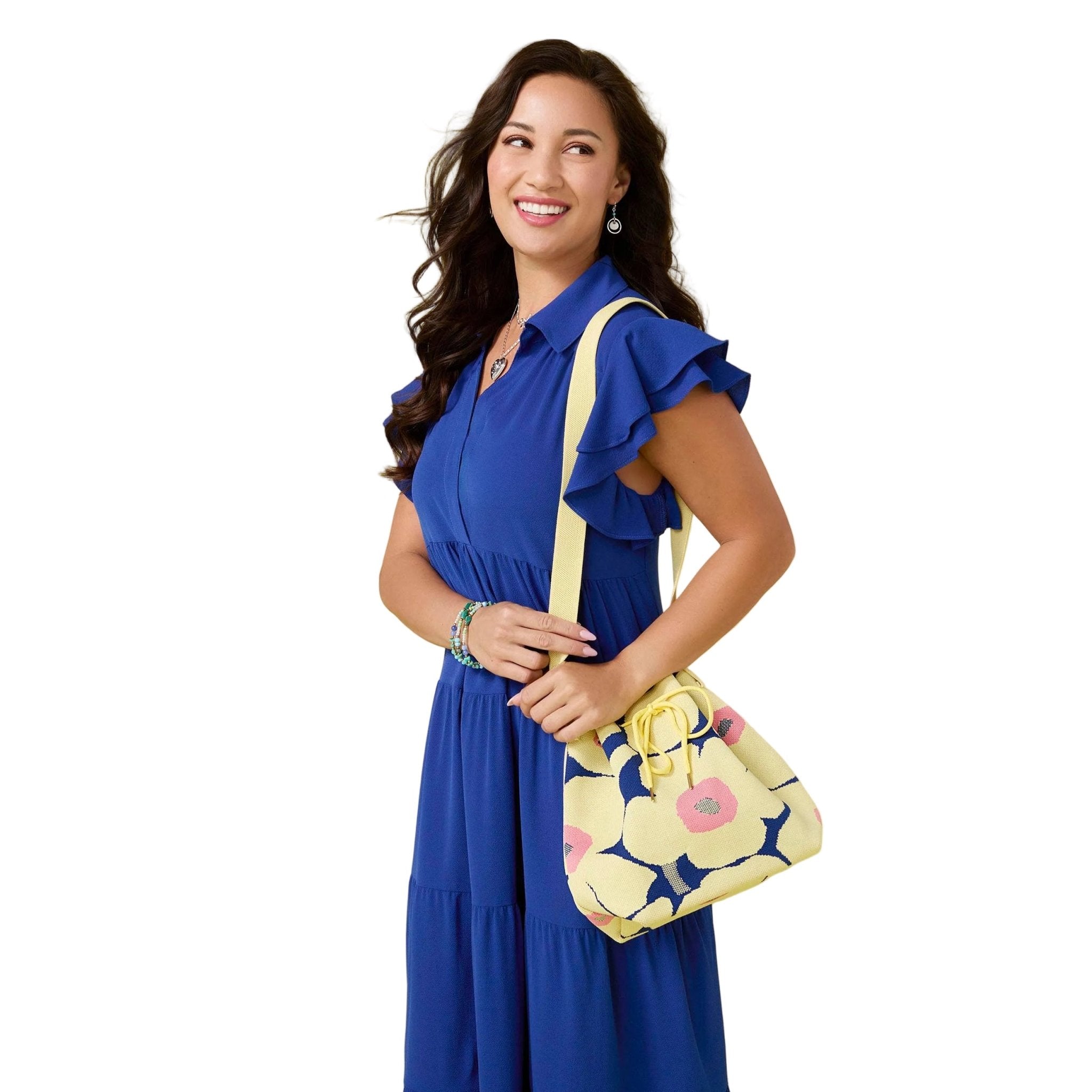 Woman in a blue dress holding a yellow floral handbag against a yellow background