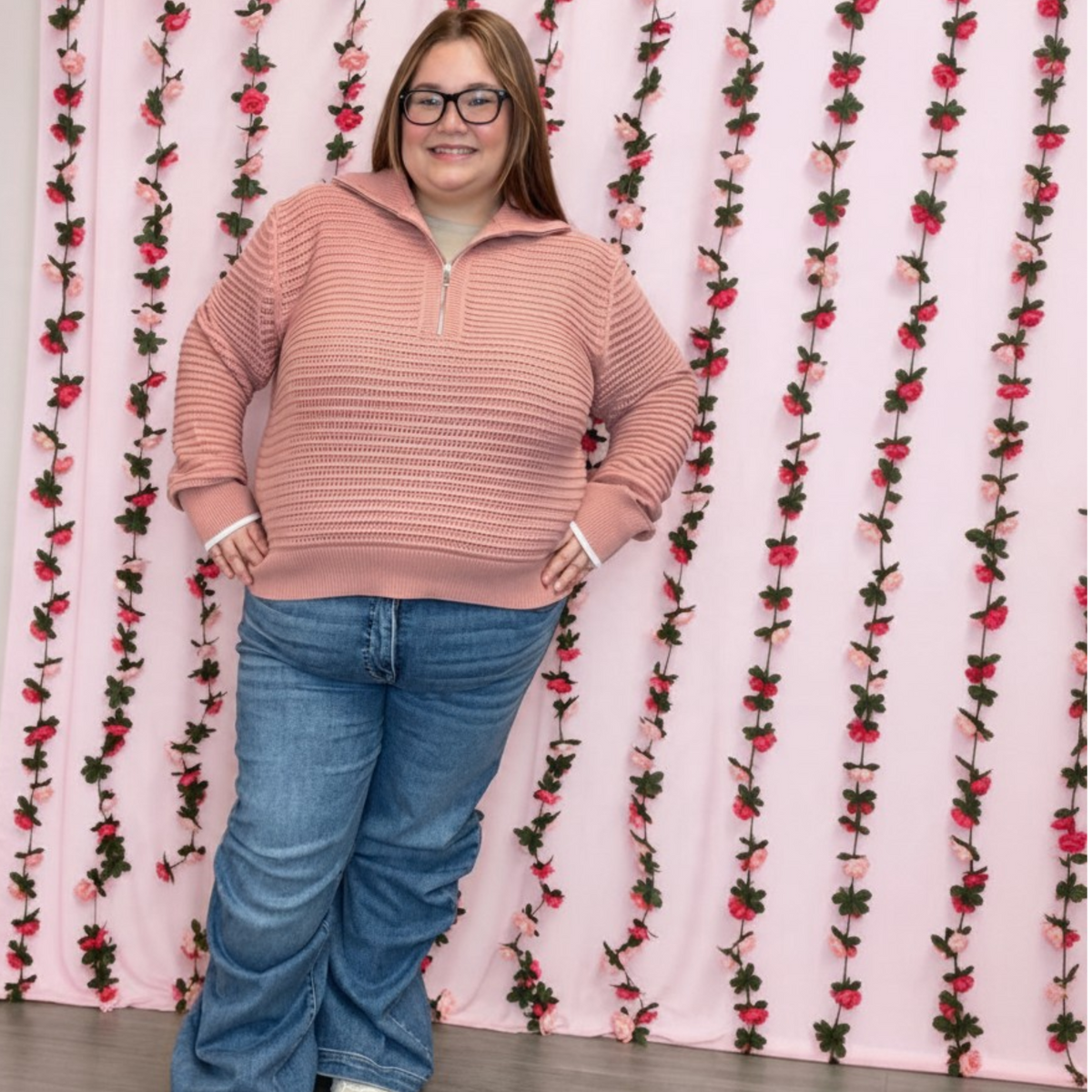 Plus size model in a dusty pink pointelle knit half zip sweater styled with wide leg jeans