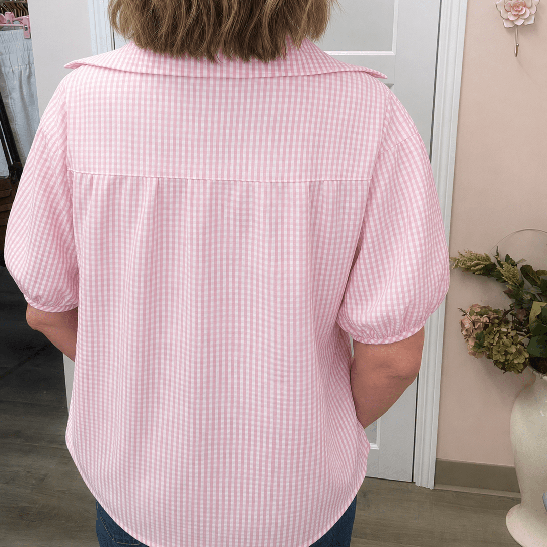 Person wearing a pink checkered shirt in a room with decor elements.