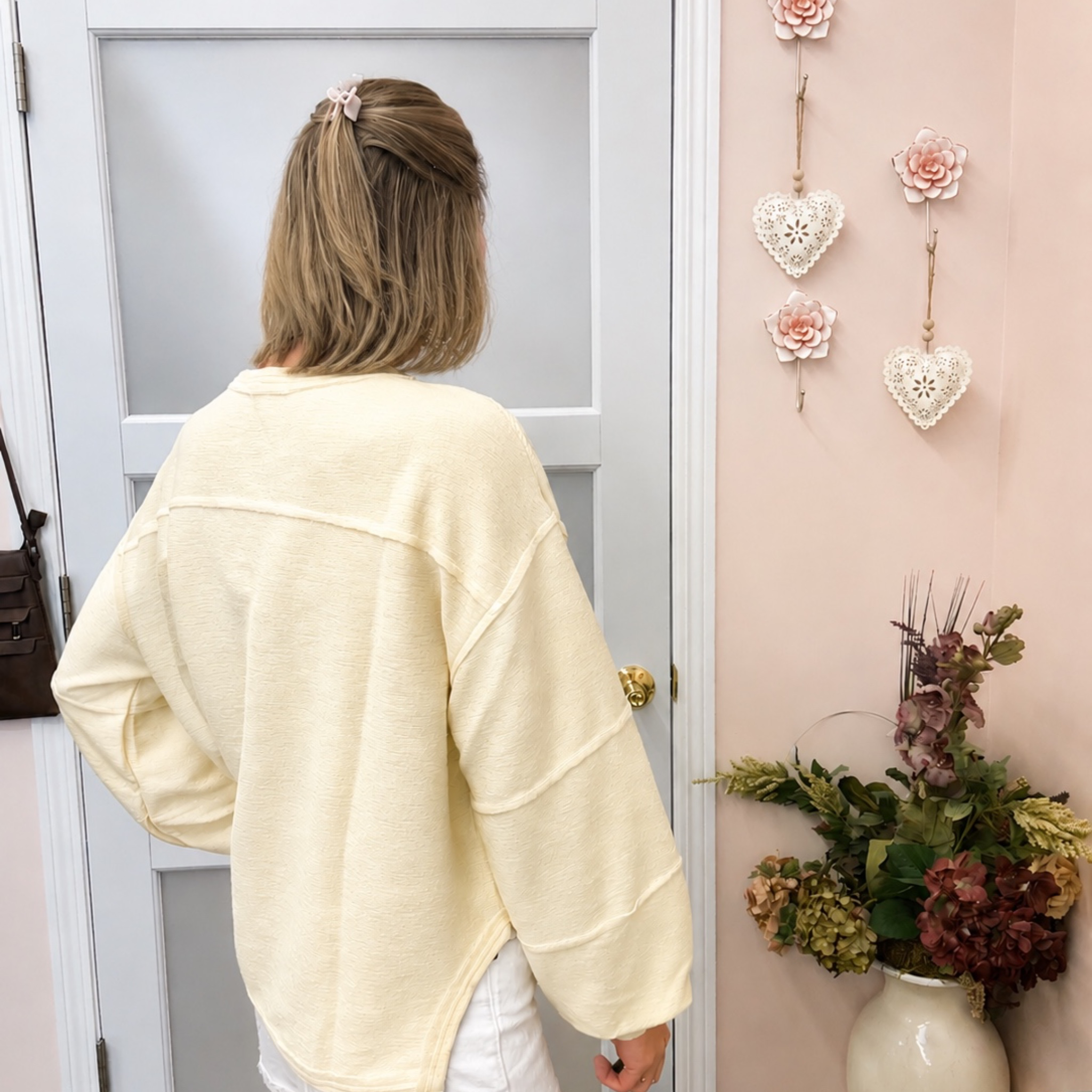 Woman in a light-colored shirt standing in a room with decorative elements.