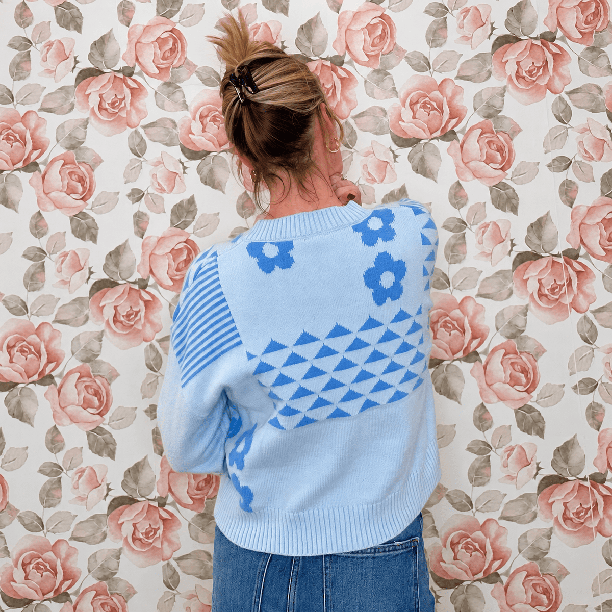 Back view of light blue floral knit sweater top with blue daisies, triangle pattern and ribbed crew neck