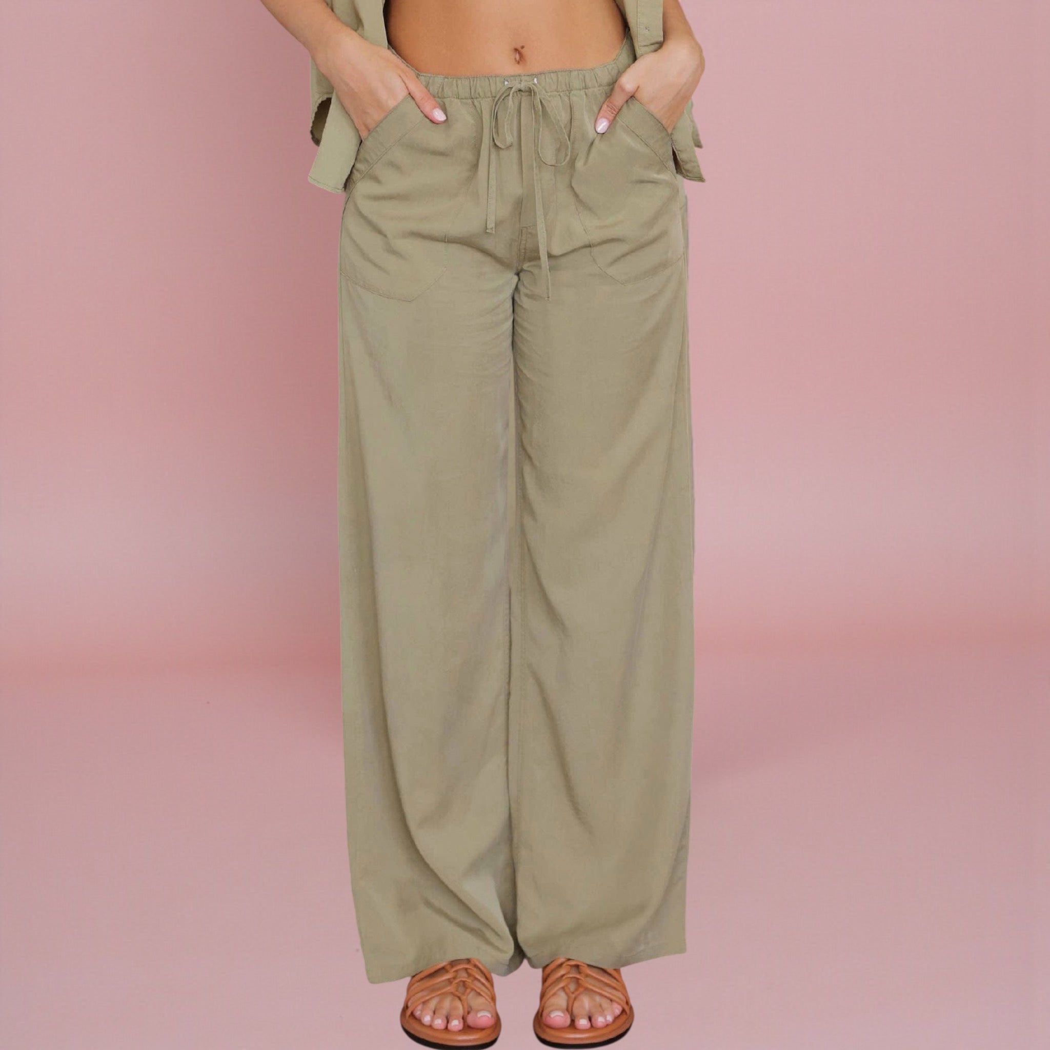 Person wearing olive green wide-leg pants on a pink background