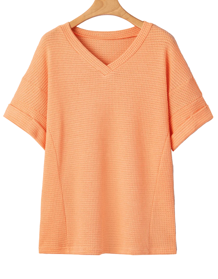 Orange textured t-shirt on a hanger against a light gray background
