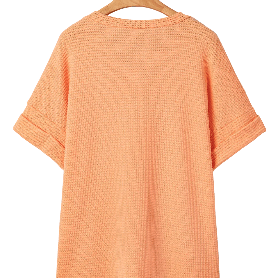 Orange textured t-shirt on a hanger against a white background