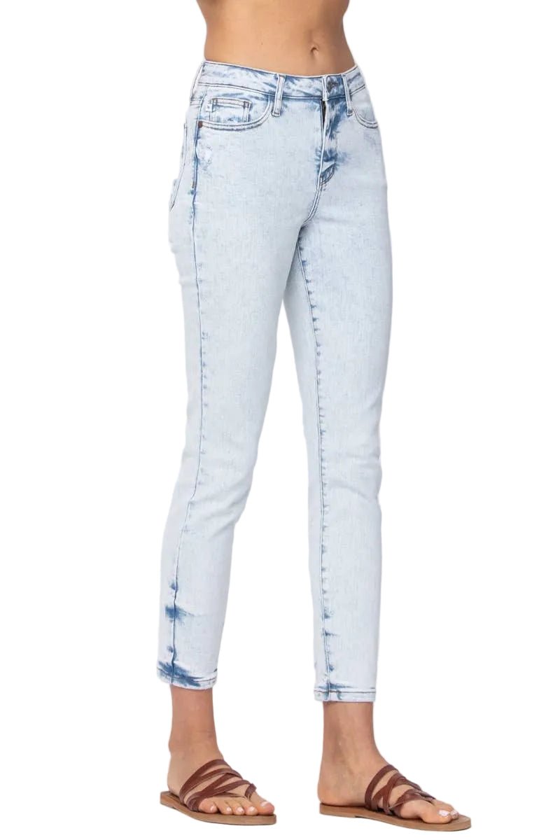 A person wearing light-wash blue cropped skinny jeans with faded detailing and brown strappy sandals, shown from the waist down against a plain light background.