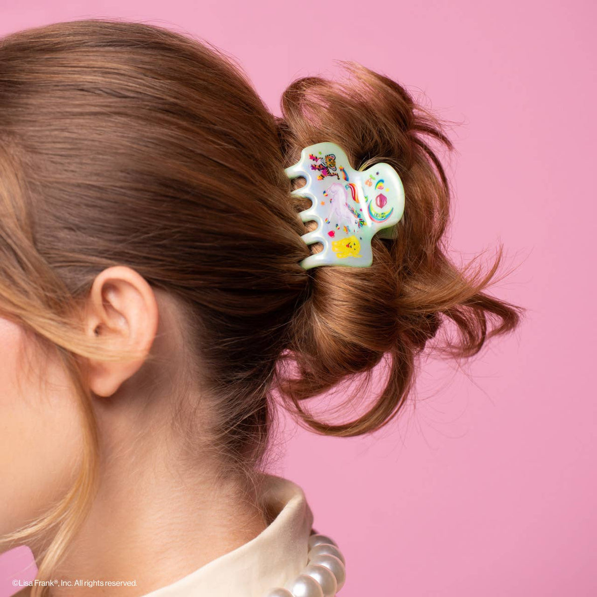 Lisa Frank Markie unicorn claw clip holding a messy bun in brown hair