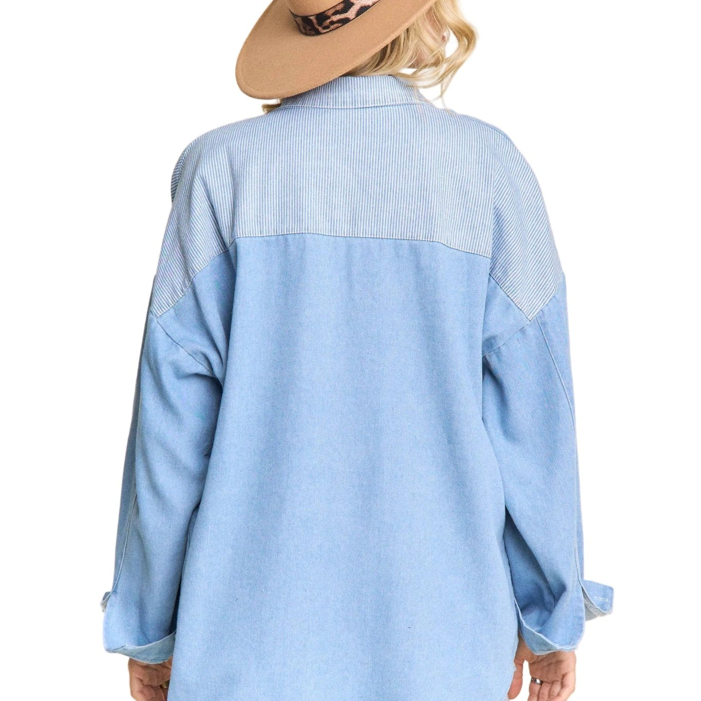 Person wearing a light blue denim shirt and a beige hat with a leopard print band on a beige background