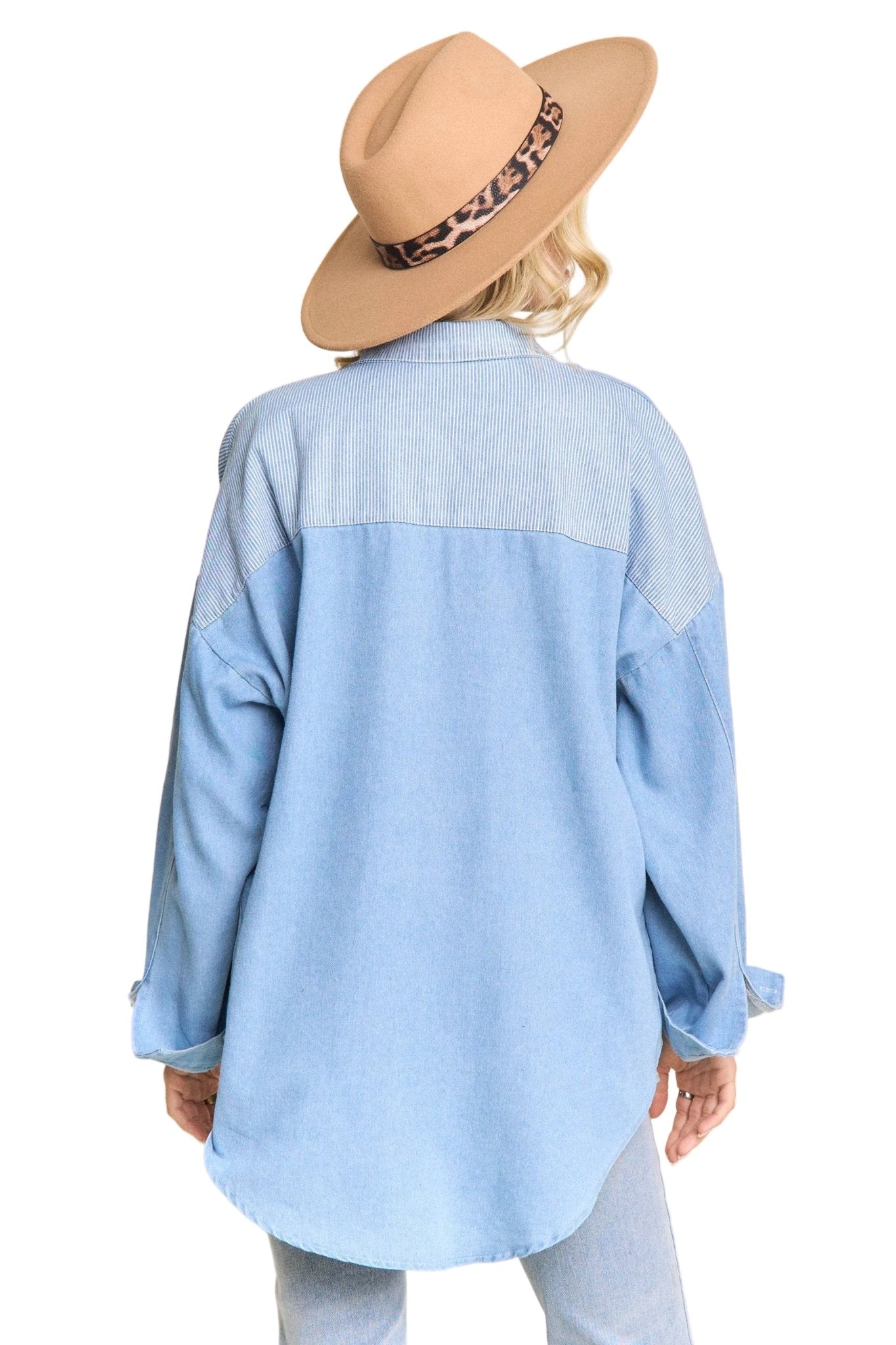 Person wearing a light blue denim shirt and a beige hat with a leopard print band on a beige background