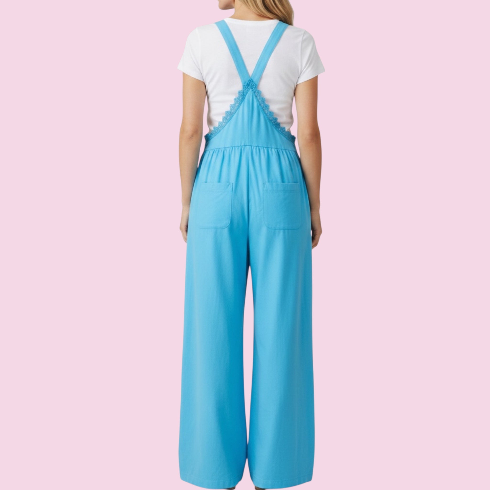 Person wearing a blue jumpsuit with a white shirt on a pink background