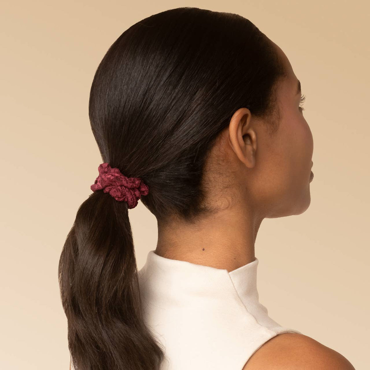 Woman with a low ponytail tied with a Cherry Lacquer burgundy lace scrunchie