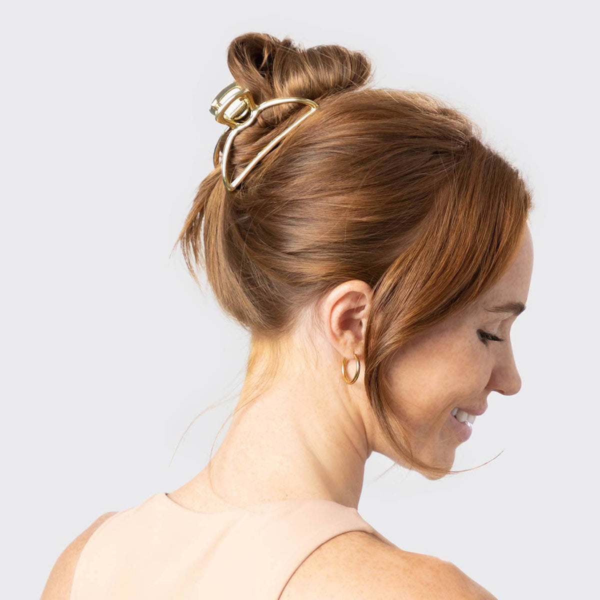 Woman with a high bun secured by a gold KITSCH open shape claw clip