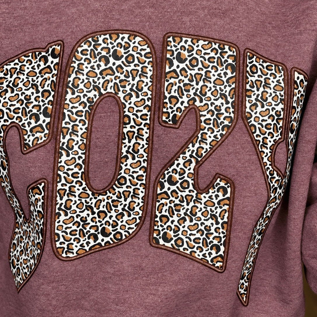 Close-up of the leopard print COZY graphic on the heather maroon sweatshirt