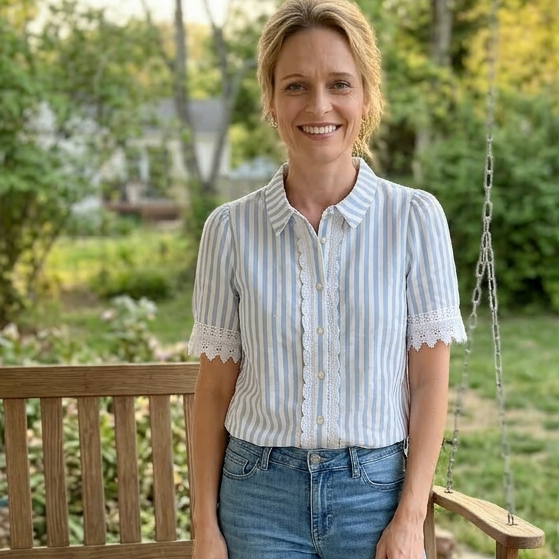 Woman standing on a porch with a wooden swing and trees in the back.