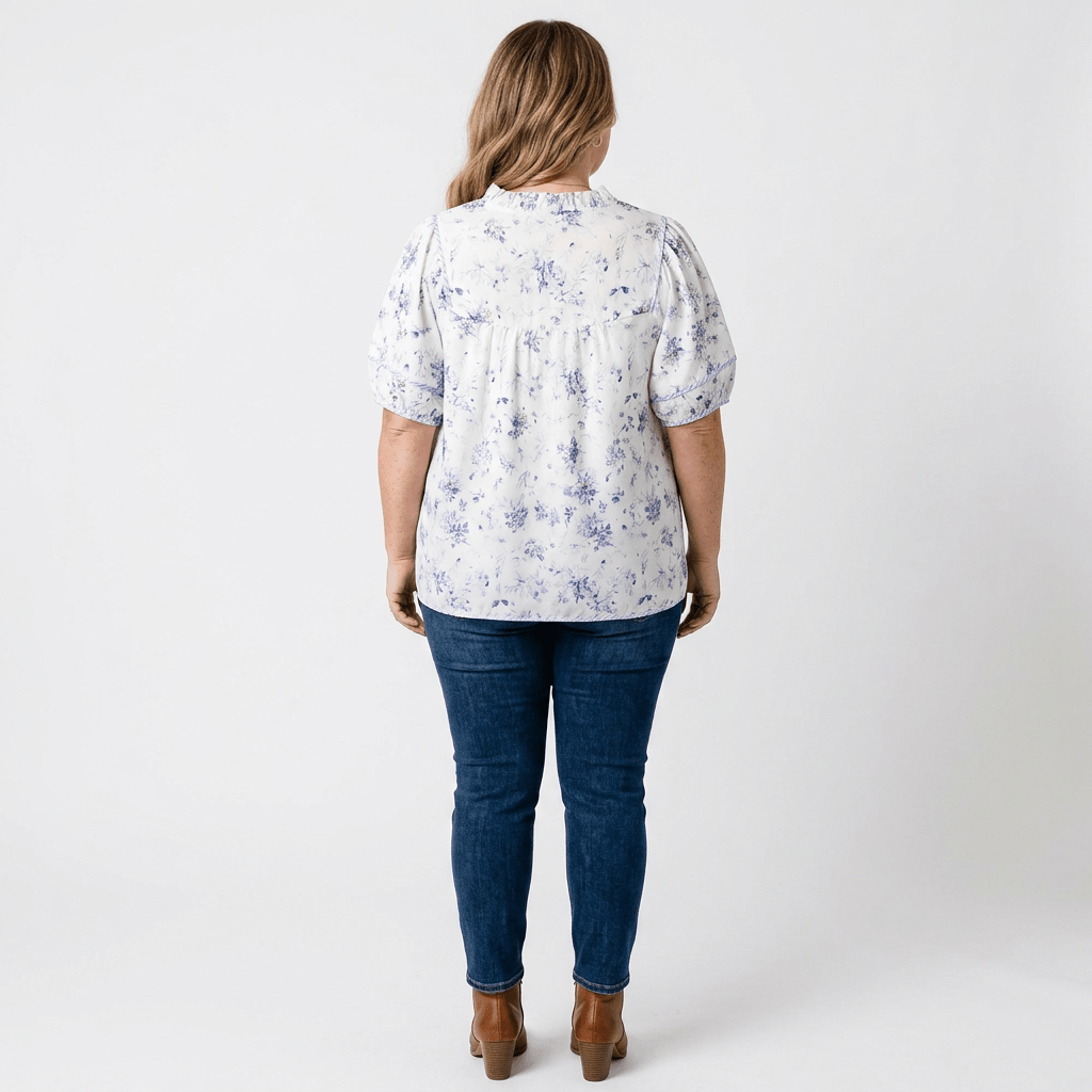 backside of woman wearing purple floral shirt with denim and brown boots. against white background.