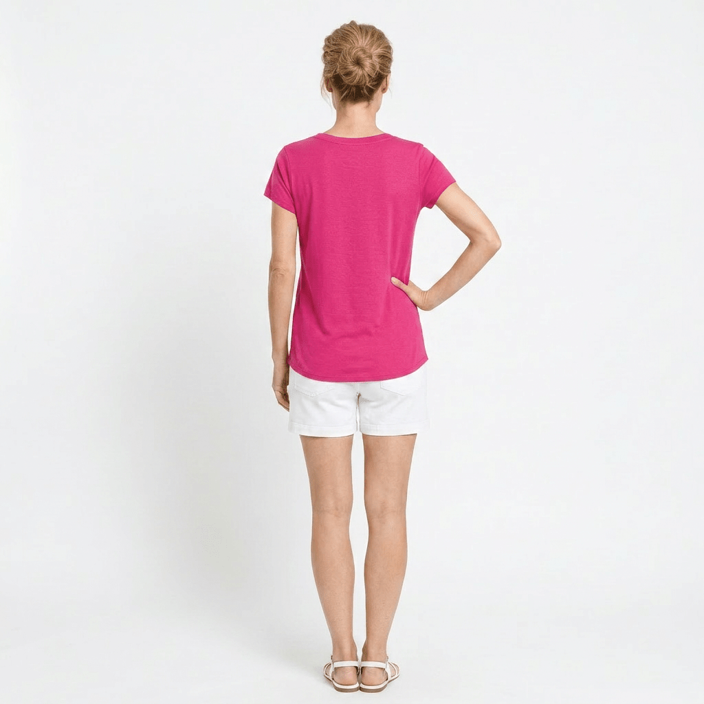 Person wearing a bright pink t-shirt and white shorts on a plain background