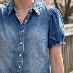 Close-up of puff sleeve denim top with pearl snap buttons
