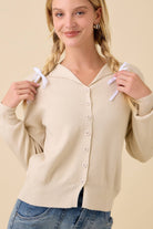 Woman wearing a natural cream collared button up cardigan sweater with jeans