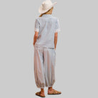 Person wearing a blue and white striped outfit with a white hat against a pink background
