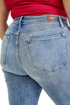 Close-up of blue jeans with a red top worn by a person.