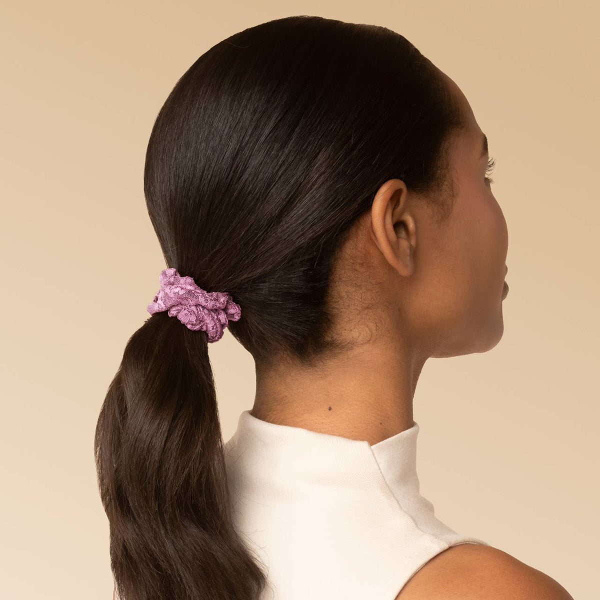 Woman with a low ponytail tied with a dusty pink ruched lace scrunchie