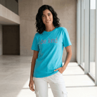 Woman wearing a blue t-shirt with 'be kind' text in a modern indoor setting