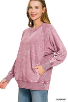 Woman wearing an oversized cabernet washed French terry pullover with raglan sleeves, ribbed cuffs and front pockets, styled with light wash jeans