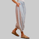 Person wearing striped pants and sandals on a pink background