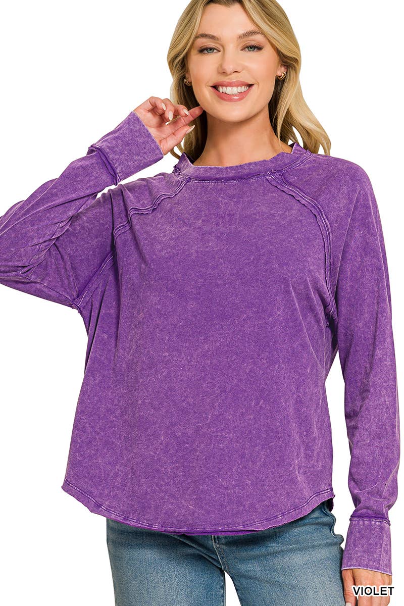 Woman wearing a violet mineral wash long sleeve top with a scoop neck, raglan sleeves and curved hem, paired with jeans