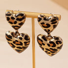 Leopard print heart-shaped earrings on a beige background