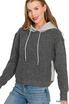 Woman wearing a charcoal textured knit hoodie sweater with a heather gray contrast hood and drawstrings, paired with jeans