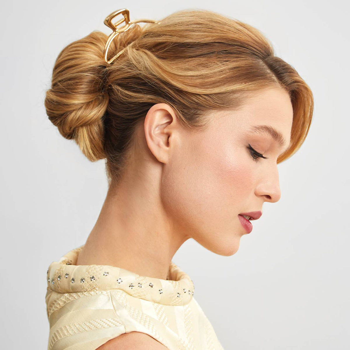 Woman with blonde hair in a twisted updo held by a gold open shape claw clip