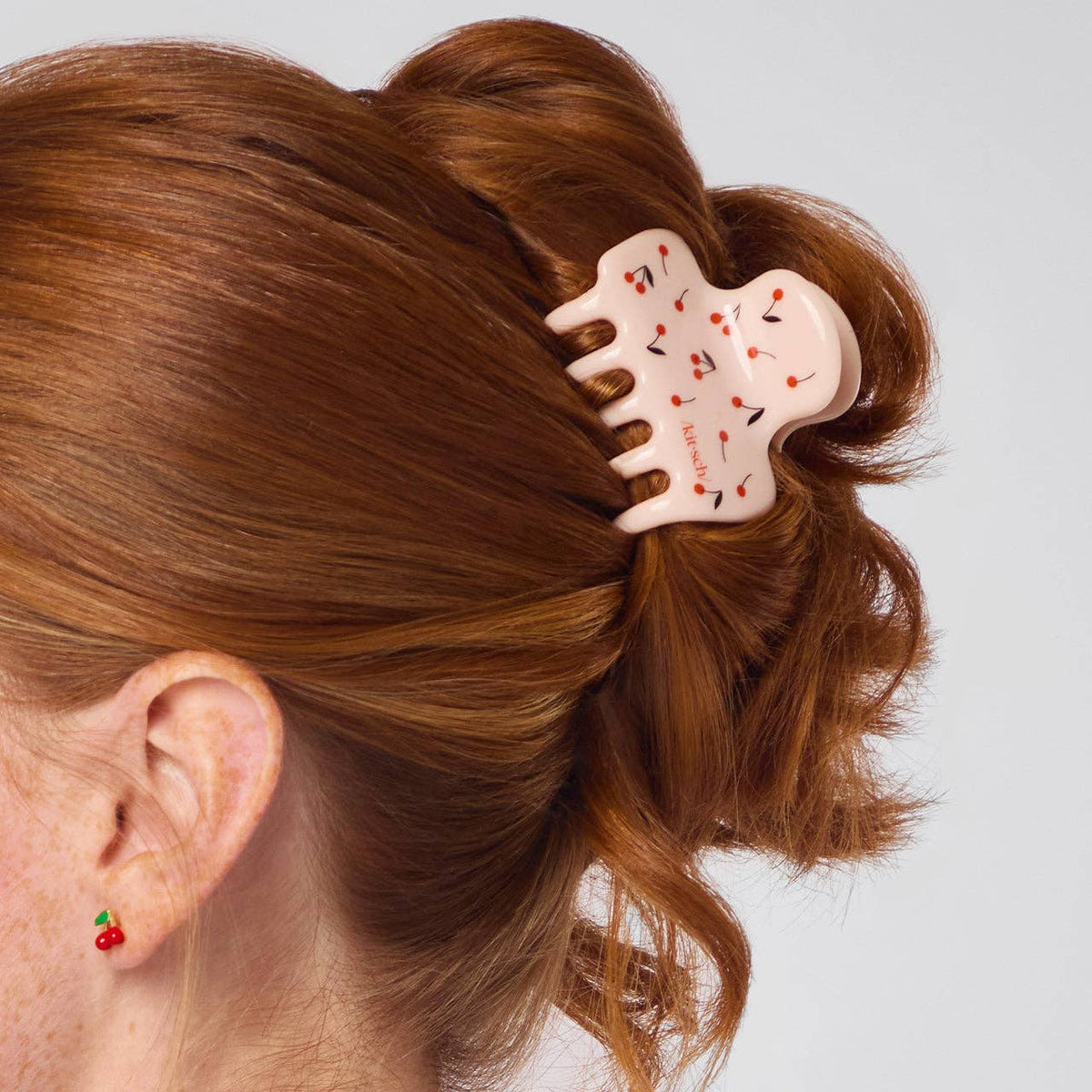 Pink cherry print Kitsch claw clip holding an updo in auburn hair