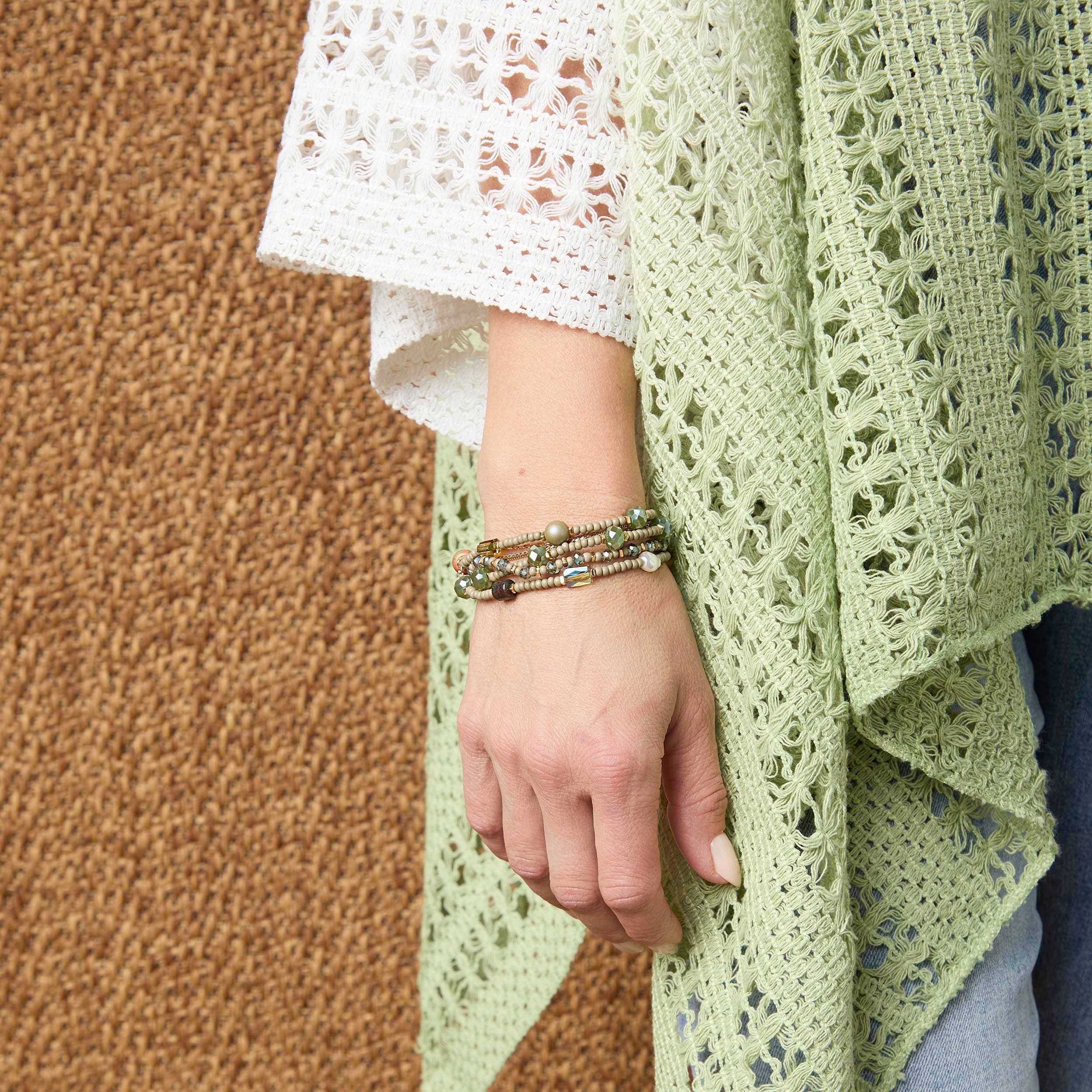 Person wearing a green lace shawl with a brown background