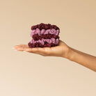 Hand holding a stack of burgundy and dusty pink KITSCH lace scrunchies