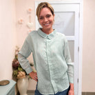 woman in mint green collard button up shirt.  flowers and a door in the background