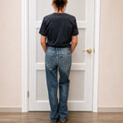 person facing a white door and wearing blue denim and blue top
