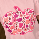 Close-up of pink tee pumpkin graphic filled with autumn leaves and florals in berry, rose and orange tones