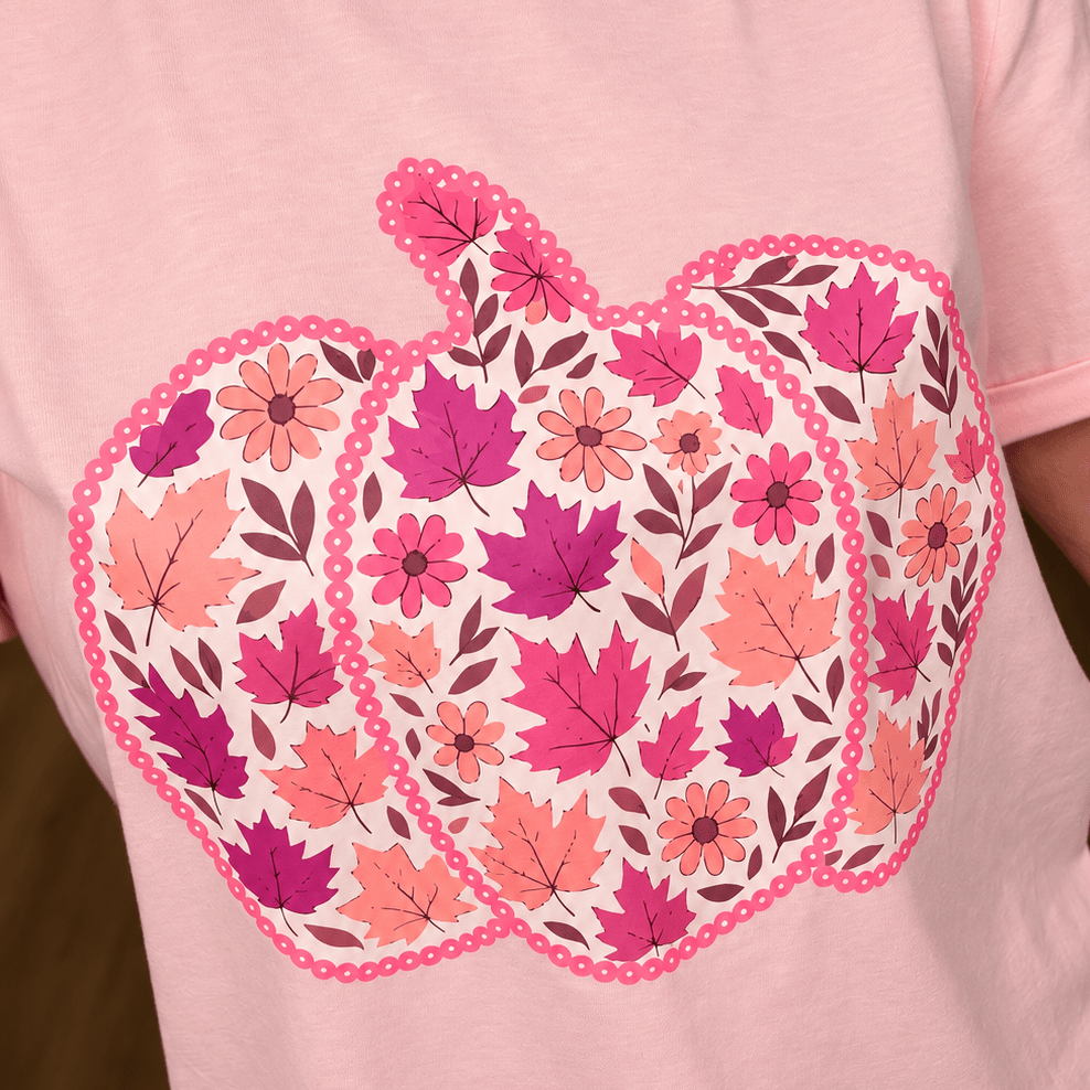 Close-up of pink tee pumpkin graphic filled with autumn leaves and florals in berry, rose and orange tones