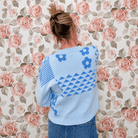 Back view of light blue floral knit sweater top with blue daisies, triangle pattern and ribbed crew neck