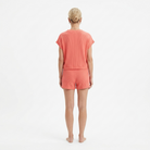 Person wearing a coral-colored outfit on a white background