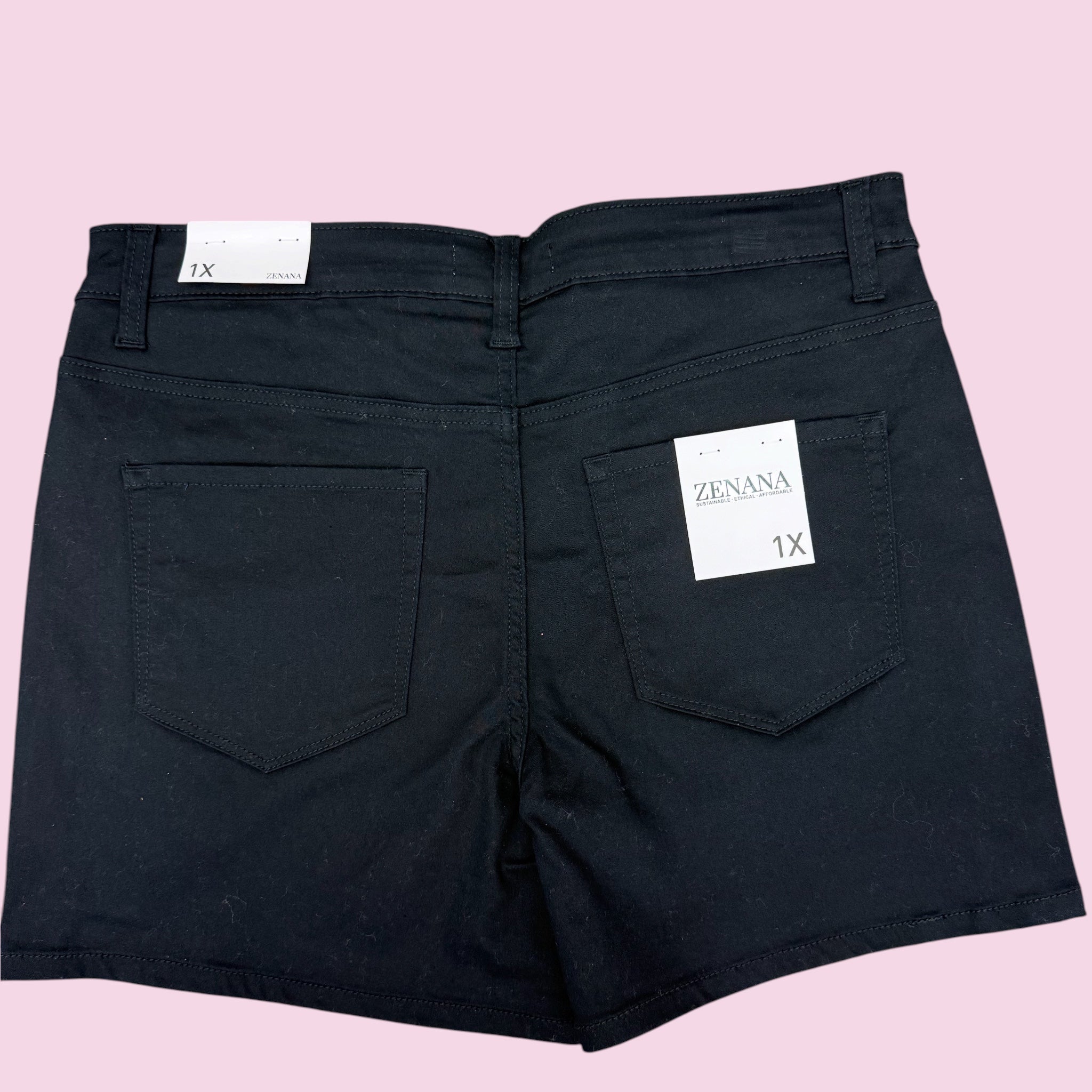 Black shorts with a brand label on a pink background