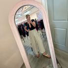 Person taking a mirror selfie in a clothing store with a decorative mirror.