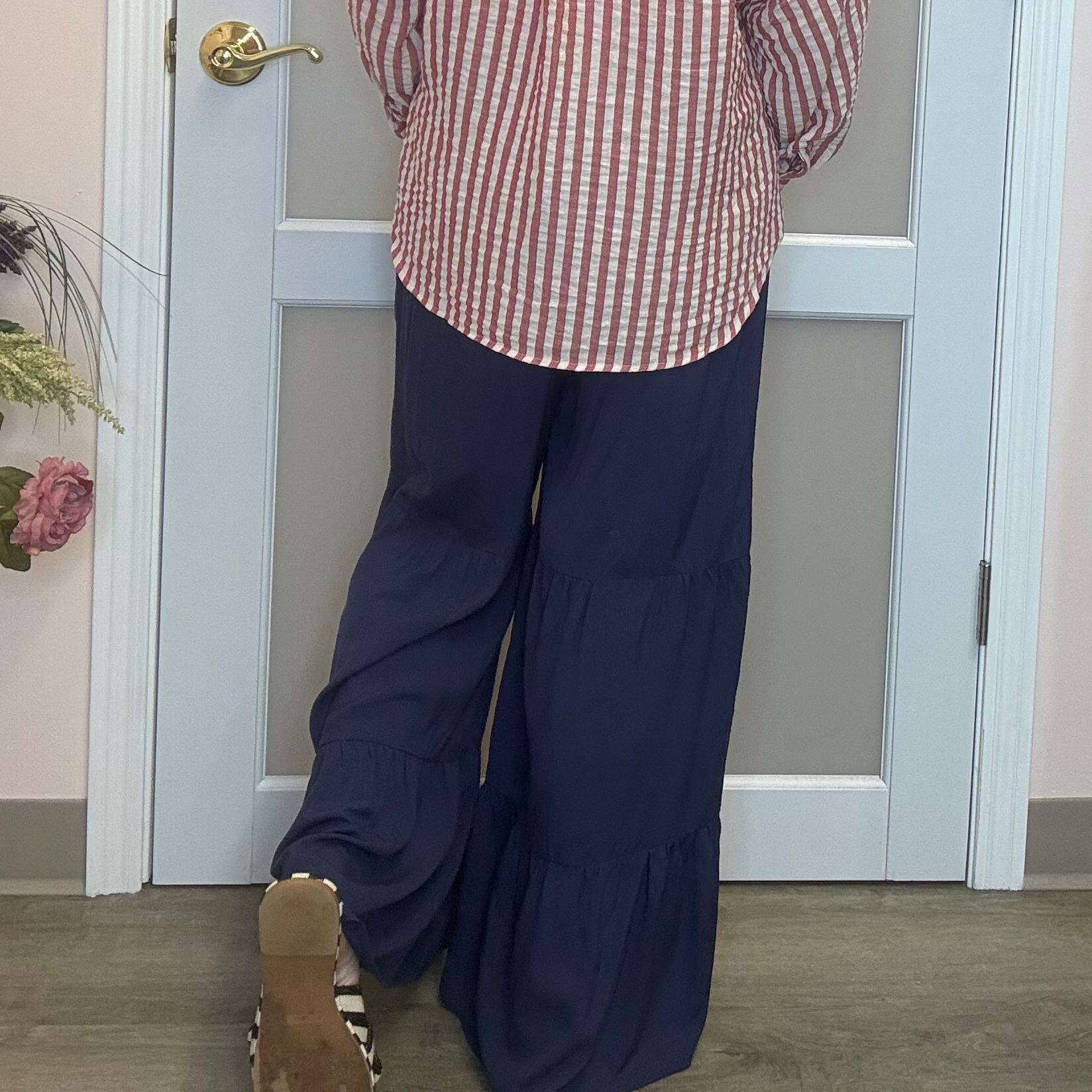 person wearing navy blue pants and the back of a red and white stripped shirt 