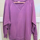 Flat lay of the plus size crewneck sweatshirt on a hanger showing the raglan sleeves, V-stitch detail at the neckline and ribbed cuffs and hem