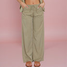 Person wearing olive green wide-leg pants on a pink background